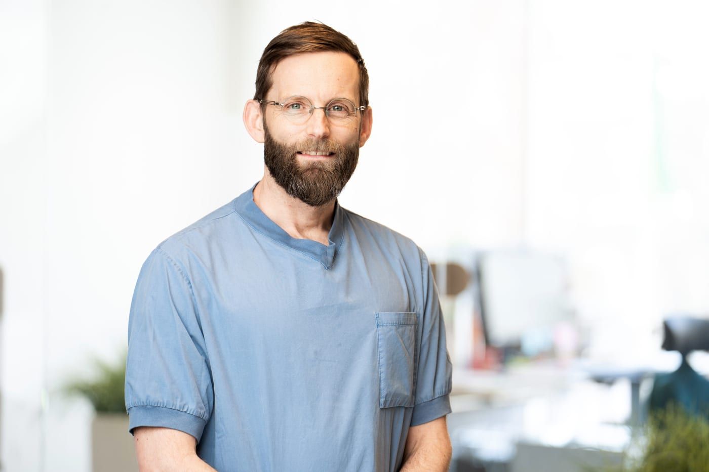 Portrait of an Aleris colleague with glasses and a beard, in a blue tunic